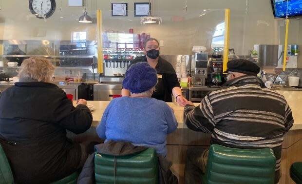 Customers at Maid Marian's Diner in Charlottetown sit at the counter seperated from staff by a clear plastic barrier.