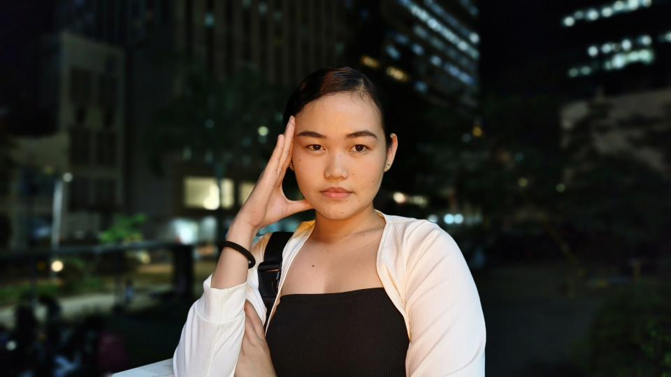 A woman smiling for a photo in front of a bustling cityscape