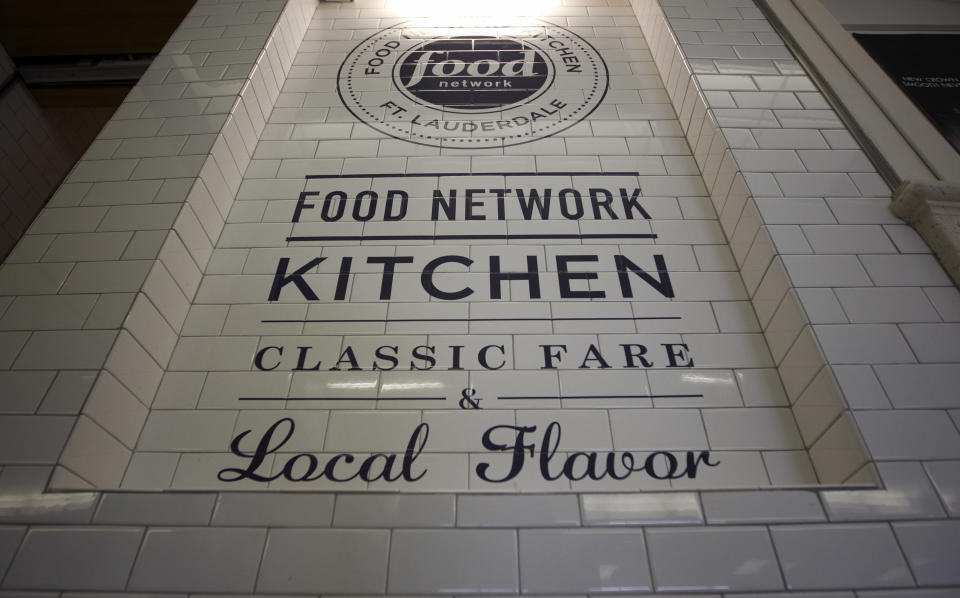 In this Wednesday, Nov. 14, 2012 photo, the logo for the Food Network Kitchen is seen at the Fort Lauderdale-Hollywood International Airport in Fort Lauderdale, Fla. Dining-on-the-go is soaring at the airport where travelers can dine at a restaurant inspired by a test kitchen. The Fort Lauderdale-Hollywood International Airport is the first outpost in the nation to offer the Food Network Kitchen, designed to look much like what you would see in the cable network’s test kitchen: a butcher block bar counter, subway tiling, stainless steel surfaces and pots and pans hanging in a row behind a cash register. (AP Photo/J Pat Carter)