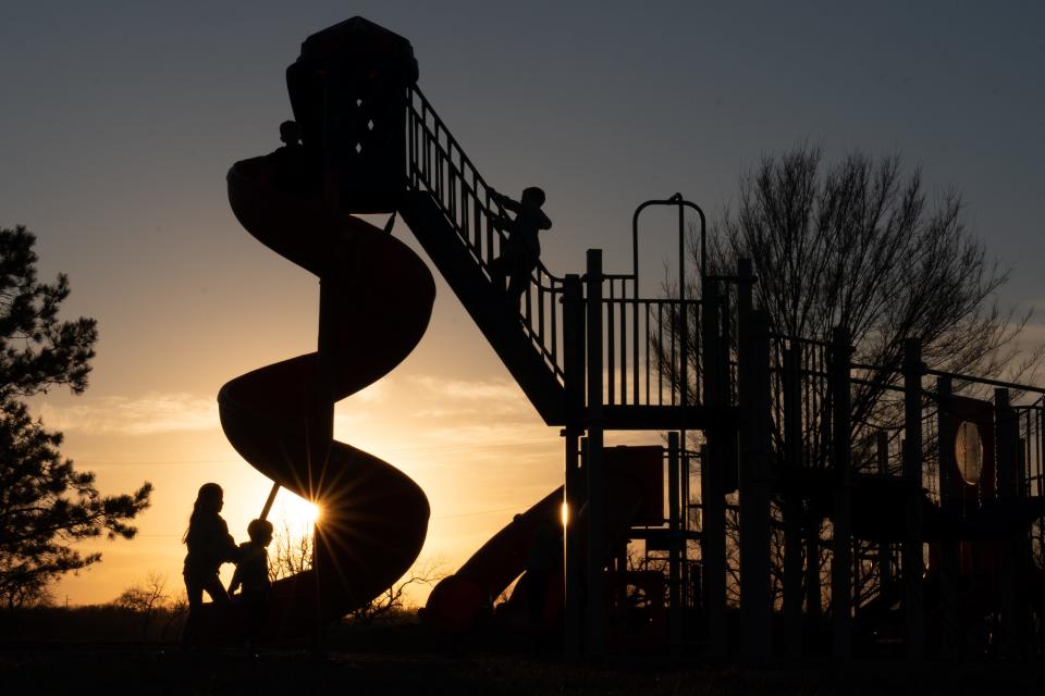 Children use the playground set at Tin Man Circle on the east side of Lake Shawnee on Wednesday evening while temperatures were in the high 50s.