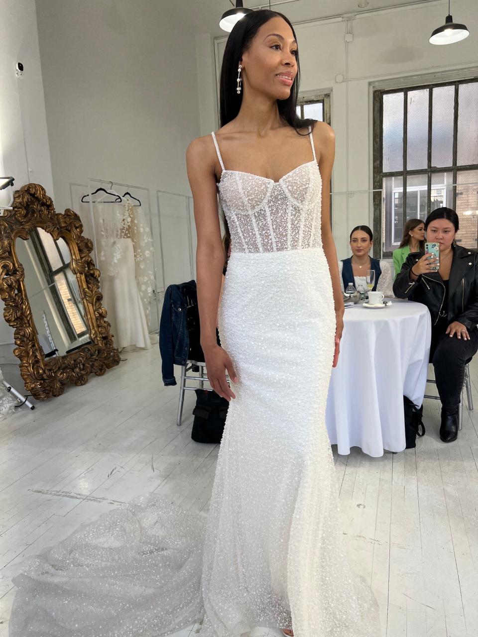 A woman poses in a sparkly wedding dress with a simple skirt.