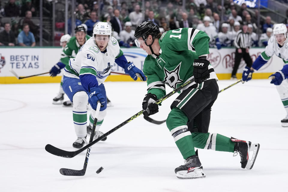 Dallas Stars center Ty Dellandrea (10) attempts to shoot as Vancouver Canucks' Guillaume Brisebois (55) defends in the first period of an NHL hockey game, Monday, Feb. 27, 2023, in Dallas. (AP Photo/Tony Gutierrez)