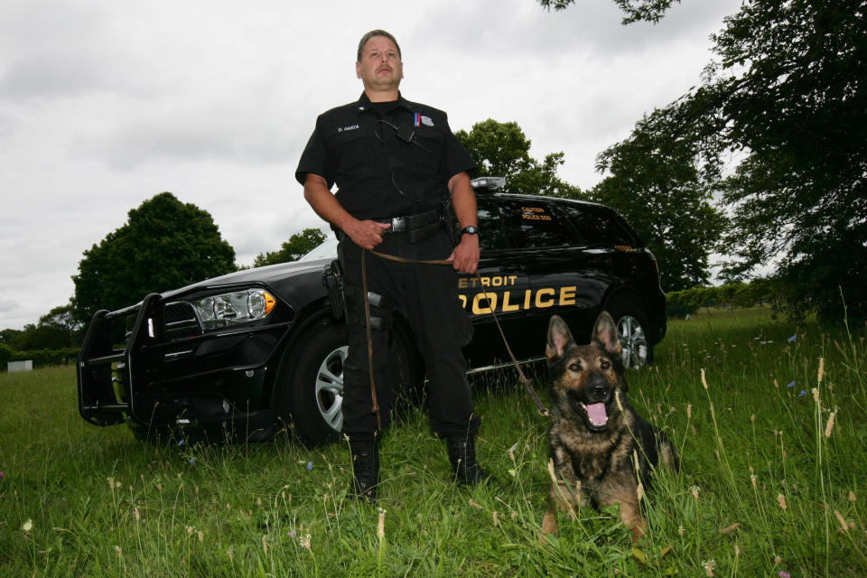 IMAGE DISTRIBUTED FOR PETARMOR - In this photo taken on Wed., July 16, 2014 in Detroit, police Sgt. Oscar Garza is seen with his dog, Mace, in the Detroit Police K9 training field. PetArmor has donated bullet-and-stab protective vests to three K-9s who work alongside officers from the Detroit Police Department. (Photo by Gary Malerba/Invision for PetArmor/AP Images)