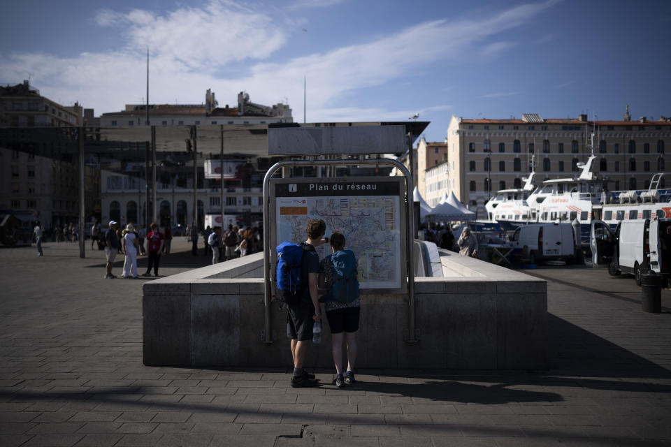 Tourists look at a map on the Vieux Port in Marseille, southern France, Friday, June 23, 2023, where the Olympic flame will arrive on May 8, 2024 aboard the Belem sailing vessel. Paris 2024 organizing committee president Tony Estanguet unveiled flame's route for the 2024 Paris Games on Friday. (AP Photo/Daniel Cole)