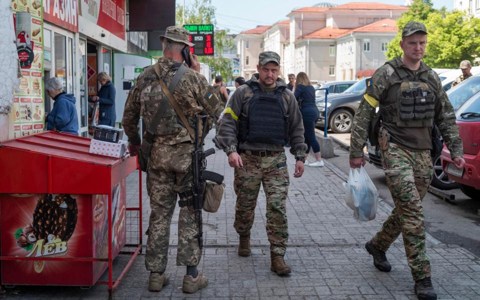 Soldiers shop for lunch among civilians from neighbouring towns waiting for evacuation buses - David Rose for The Telegraph