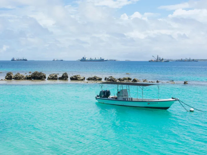 Majuro Marshall Islands boat on blue water in port on rocks.