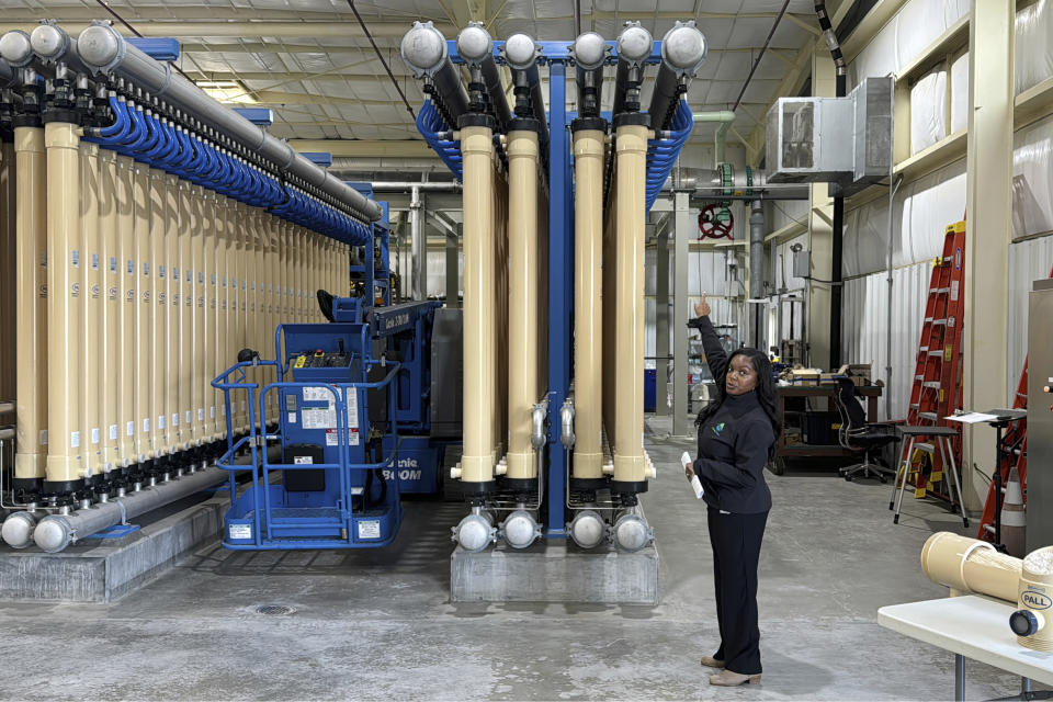 Lakeisha Bryant, public information representative at the Santa Clara Valley Water District, points to a water micro-filtration system at the Silicon Valley Advance Water Purification Center, Wednesday, Dec. 13, 2023, in San Jose, Calif. California regulators are set to vote on new rules Tuesday, Dec. 19, to let water agencies recycle wastewater and put it right back into the pipes that carry drinking water to homes, schools and businesses. (AP Photo/Terry Chea)