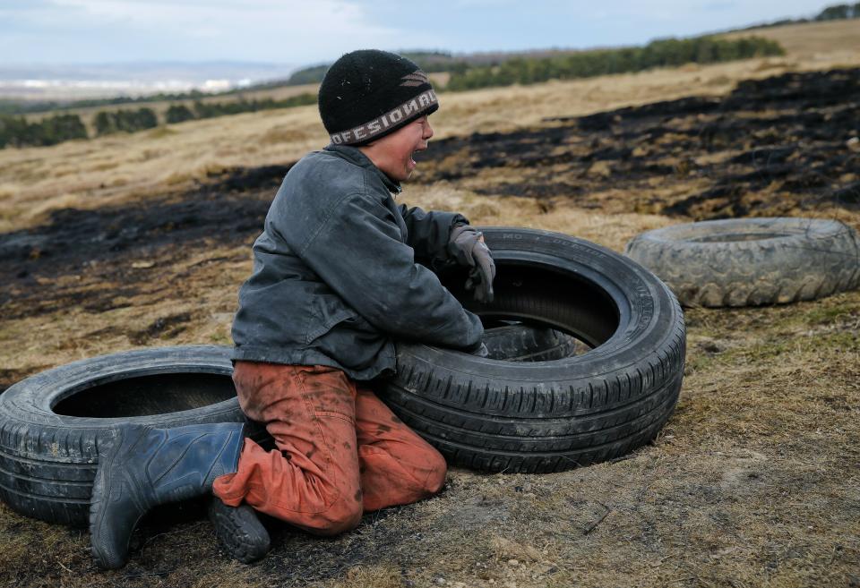 In this photo taken on Sunday, March 10, 2019, a child cries after arguing with another during a ritual marking the upcoming Clean Monday, the beginning of the Great Lent, 40 days ahead of Orthodox Easter, on the hills surrounding the village of Poplaca, in central Romania's Transylvania region. Romanian villagers burn piles of used tires then spin them in the Transylvanian hills in a ritual they believe will ward off evil spirits as they begin a period of 40 days of abstention, when Orthodox Christians cut out meat, fish, eggs, and dairy. (AP Photo/Vadim Ghirda)