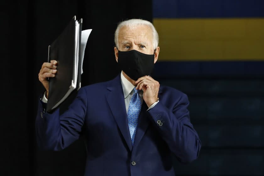 Democratic presidential candidate, former Vice President Joe Biden puts on a face mask to protect against the spread of the new coronavirus as he departs after speaking at Alexis Dupont High School in Wilmington, Del., Tuesday, June 30, 2020. (AP Photo/Patrick Semansky)