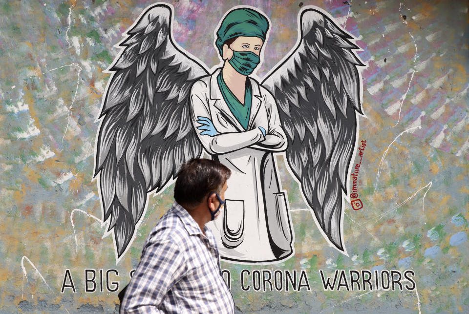 A man walks past a graffiti saluting frontline workers in the fight against the coronavirus pandemic in New Delhi, India, Wednesday, June 9, 2021. (AP Photo/Amit Sharma)