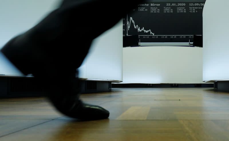 FILE PHOTO: A trader walks past the German share price index DAX graph at Frankfurt's stock exchange in Frankfurt