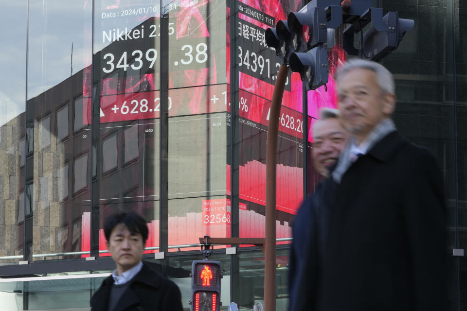 People walk past an electronic stock board showing Japan's Nikkei 225 index at a securities firm Wednesday, Jan. 10, 2024 in Tokyo. (AP Photo/Shuji Kajiyama)