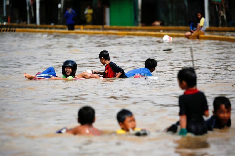 Children play in the floodwaters that hit the Jatinegara area after heavy rains in Jakarta