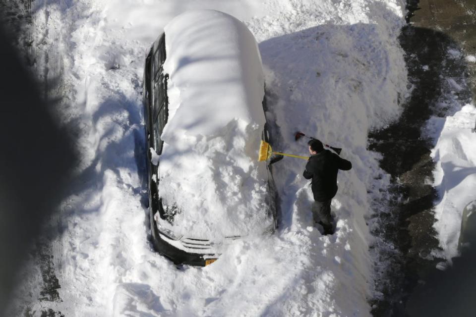 A man clears snow from his car in the Chinatown neighborhood in New York on Sunday, Jan. 24, 2016. Millions of Americans began digging out Sunday from a mammoth blizzard that set a new single-day snowfall record in Washington and New York City. [AP Photo/Peter Morgan]