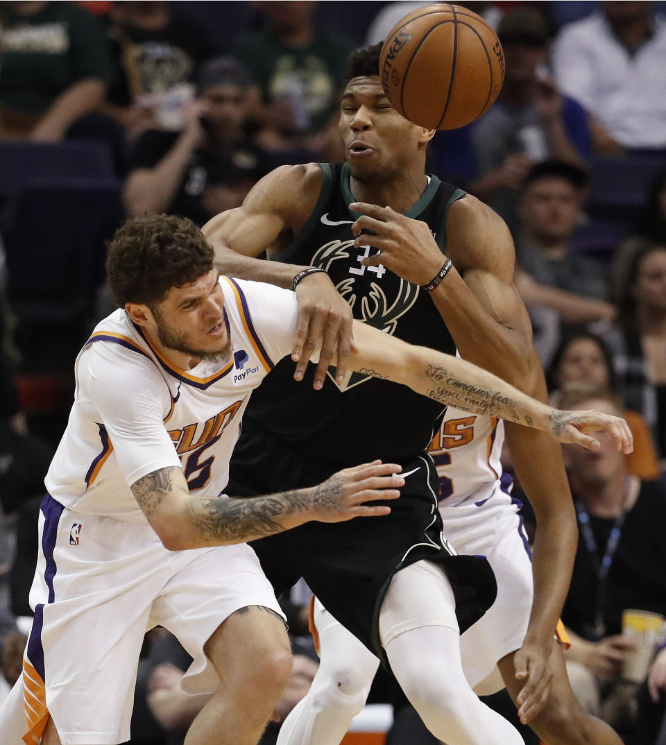 Milwaukee Bucks forward Giannis Antetokounmpo (34) and Phoenix Suns guard Tyler Johnson, left, battle for the ball during the first half of an NBA basketball game, Monday, March 4, 2019, in Phoenix. (AP Photo/Matt York)