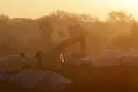 A bulldozer is used to remove debris as workmen tear down makeshift shelters at sunrise during the dismantlement of the camp called the "Jungle" in Calais, France, October 27, 2016. REUTERS/Philippe Wojazer