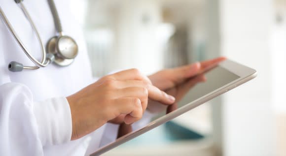 A doctor touches the screen of an iPad.