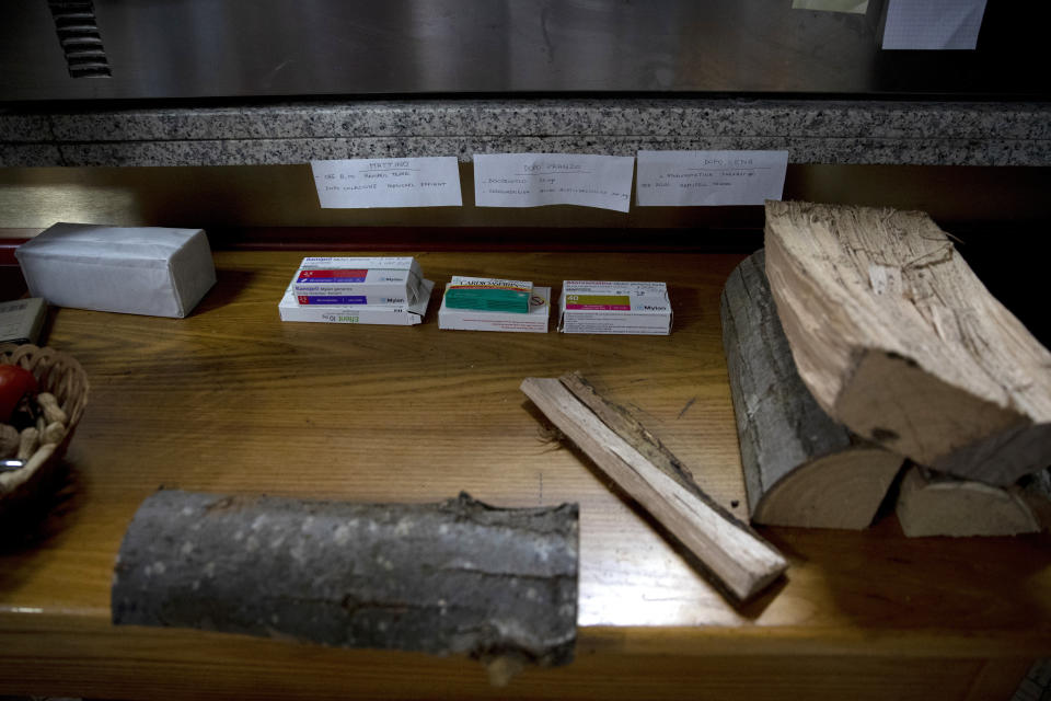 Medicine packages are placed beneath notes indicating their daily routine, next to logs for a wood oven in the home of a COVID-19 patient in Travo, near Piacenza, Italy, Wednesday, Dec. 2, 2020. (AP Photo/Antonio Calanni)