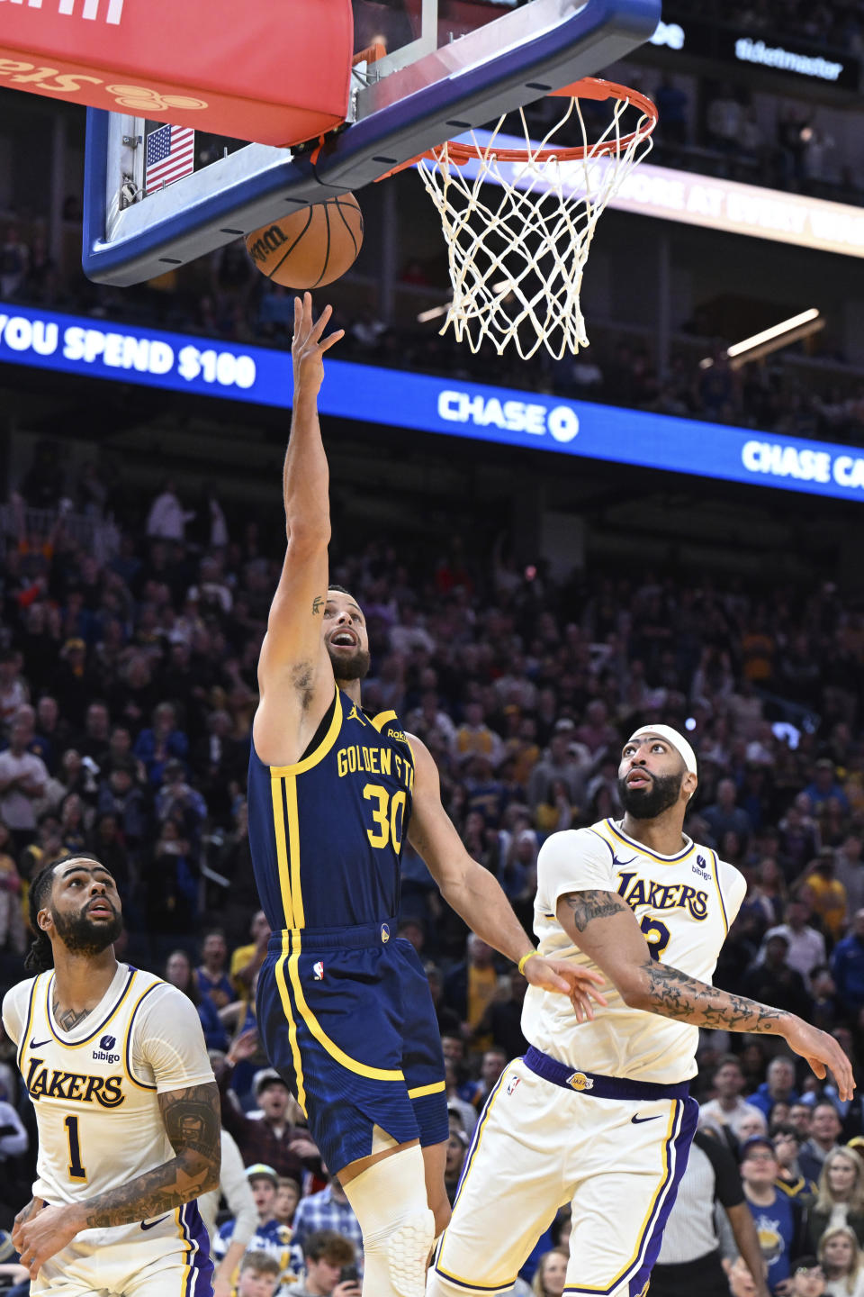 Golden State Warriors guard Stephen Curry (30) scores from between Los Angeles Lakers guard D'Angelo Russell (1) and forward Anthony Davis (3) during the second half of an NBA basketball game Saturday, Jan. 27, 2024, in San Francisco. (AP Photo/Nic Coury)