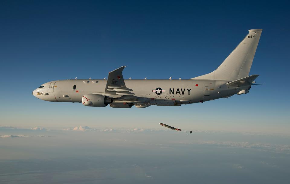 A P-8A Poseidon plane in the sky dropping a device.