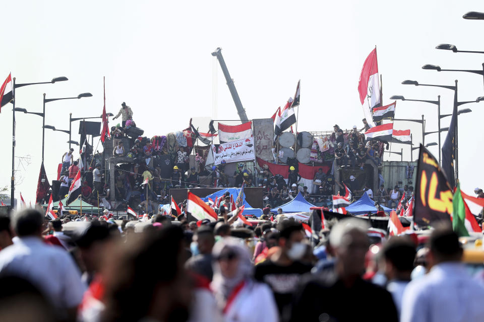 Anti-government protesters stand on barriers set by Iraqi security forces to close a bridge leading to the Green Zone government areas during ongoing protests in Baghdad, Iraq, Monday, Nov. 4, 2019. (AP Photo/Hadi Mizban)