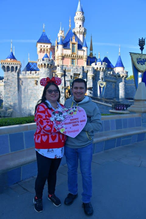 Couple in front of castle at Disneyland on Valentine's Day.