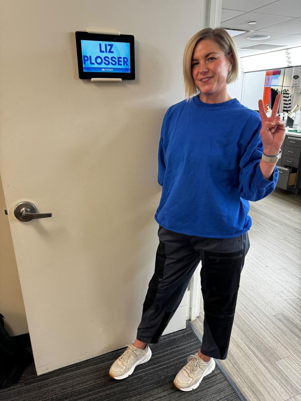 a person standing in front of a door and holding up a peace sign