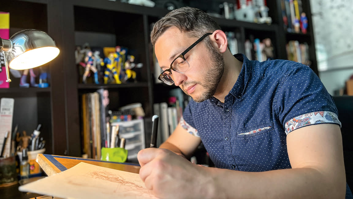  Artist in residence; Joe Quinones sits at a desk drawing. 