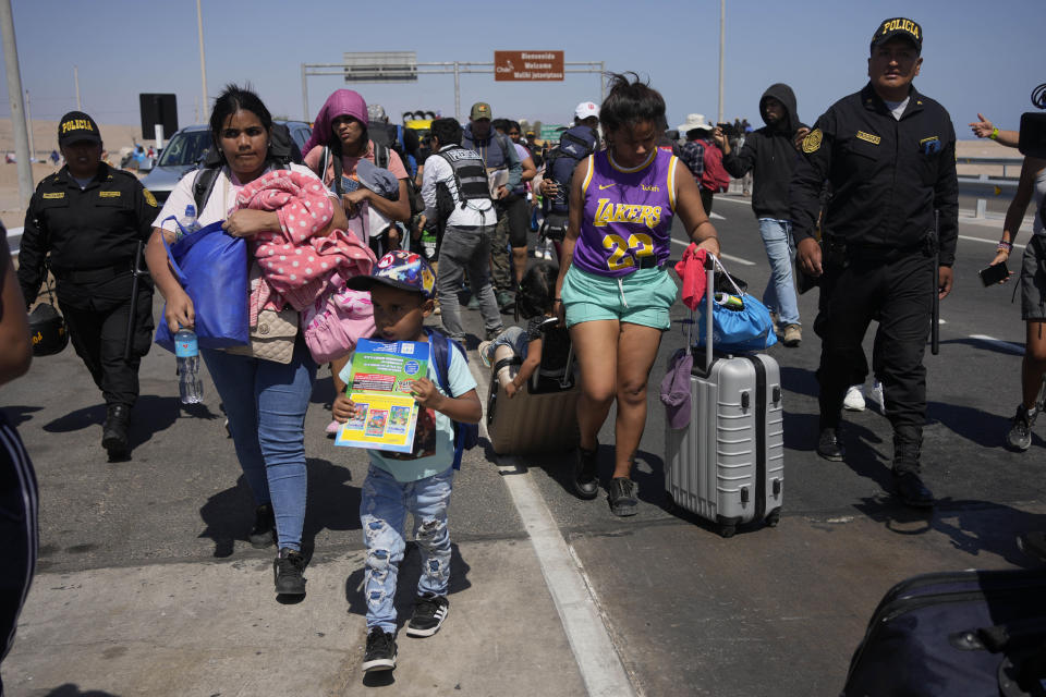 Venezuelan migrants are escorted by Peruvian police to a migration office on the border with Chile in Tacna, Peru, Friday, April 28, 2023. A migration crisis at the border between Chile and Peru intensified Thursday as hundreds of people remained stranded, unable to cross into Peru. (AP Photo/Martin Mejia)