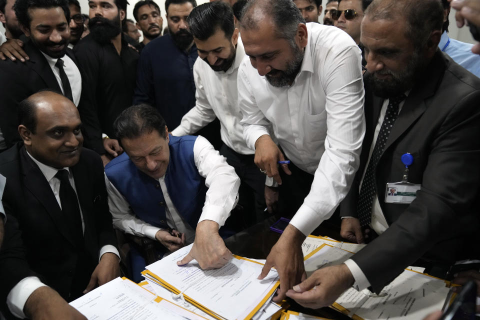 Pakistan's former Prime Minister Imran Khan sign documents as he submits surety bond over his bails in different cases at an office of Lahore High Court in Lahore, Pakistan, Tuesday, July 18, 2023. (AP Photo/K.M. Chaudary)