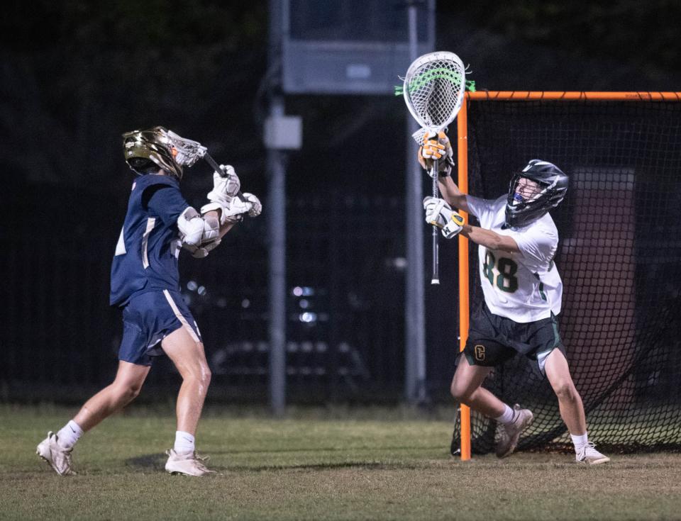 Roger Ostrander (21) gets set to shoot and score to take a 3-1 Dolphins lead during the Gulf Breeze vs Catholic boys lacrosse game at Pensacola Catholic High School on Friday, March 31, 2023.