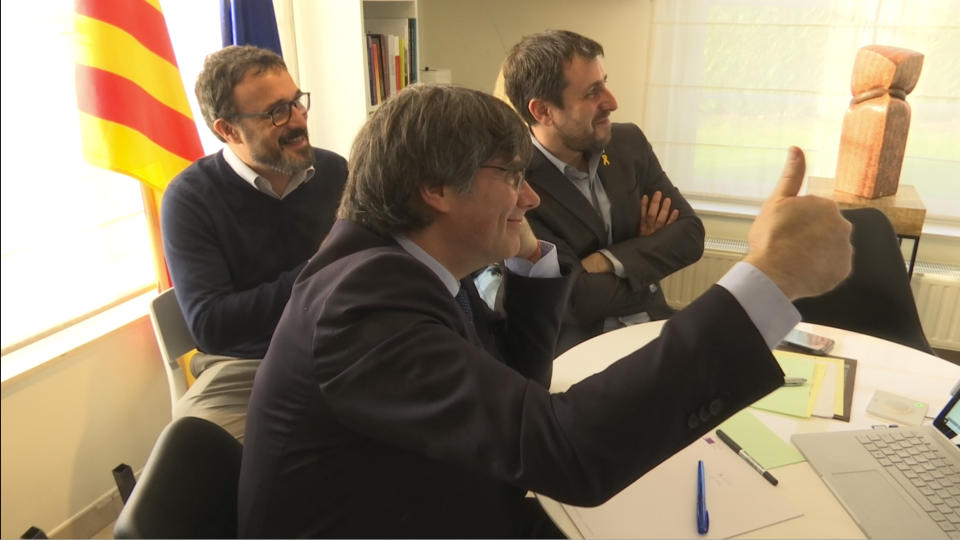 In this framegrab taken from Associated Press Television News on Thursday Dec. 19, 2019, Catalonia's former regional president Carles Puigdemont and Toni Comín have a celebration via video conference in Waterloo, Belgium with other Catalan leaders. Europe's top court ruled Thursday that a former vice president of Spain's Catalonia region, Oriol Junqueras, who is serving a prison sentence for launching a banned independence referendum should have the right to parliamentary immunity. (APTN via AP)