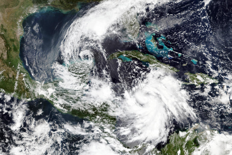 En esta imagen por satélite del 5 de octubre de 2020 proporcionada por NASA Worldview, Earth Observing System Data and Information System (EOSDIS), la tormenta tropical Gamma, a la izquierda, que castigó parte de México durante el fin de semana, y el huracán Delta, abajo a la derecha, que gana fuerza en un rumbo que lo llevará junto a las Islas Caimán el martes por la mañana. (NASA via AP)