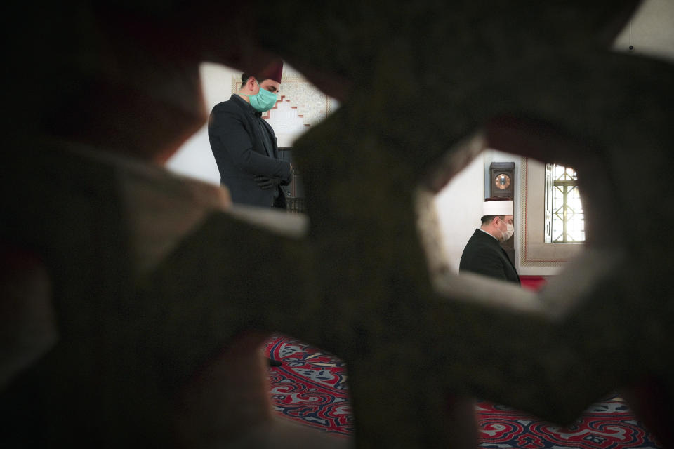 In this Thursday, April 9, 2020 photo clerics stand inside the 16th century built Gazi Husrev-beg Mosque in Sarajevo, Bosnia, as worshipers stay away due to the national lockdown the authorities have imposed attempting to limit the spread of the new coronavirus. (AP Photo/Kemal Softic)