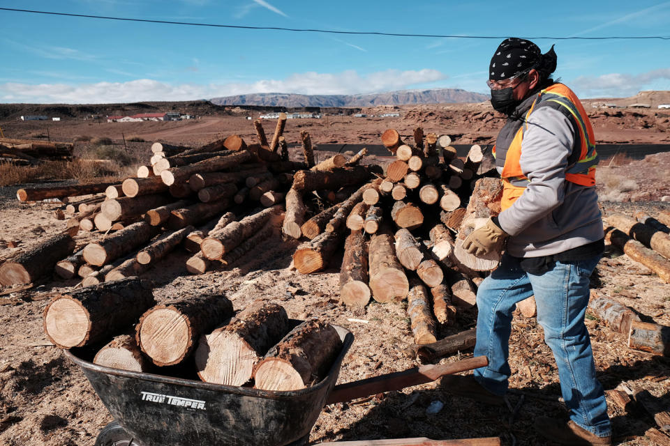 A member of the Navajo community loads wood for delivery to homes on a reservation in Cameron, Ariz., in 2021.  The wood was accessed through the National Forest Foundation's Wood for Life initiative.  (Spencer Platt / Getty Images)