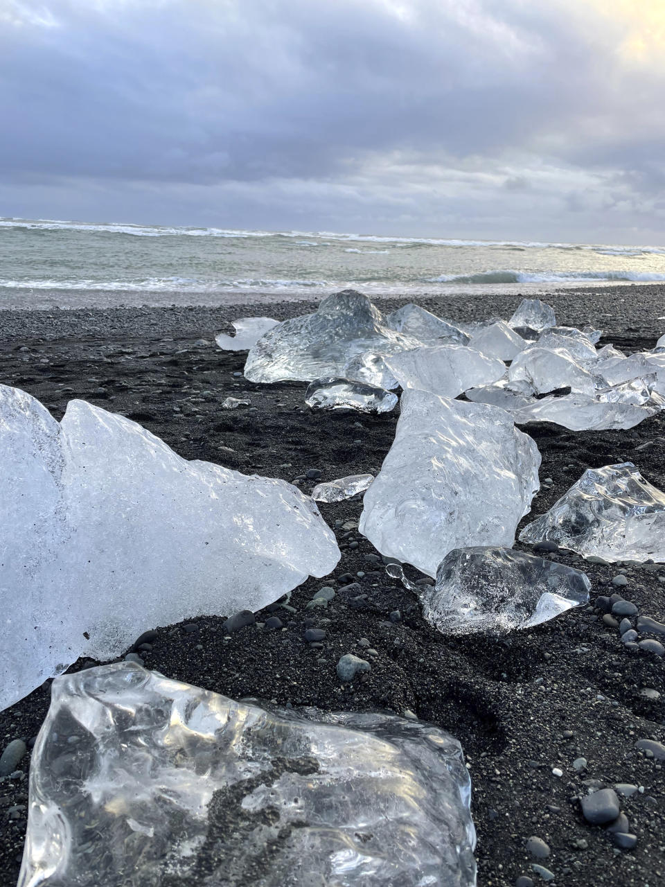 This Nov. 18, 2023 image provided by Beth Harpaz shows mini-icebergs on Diamond Beach on Iceland's South Coast. The glistening ice chunks break off from a glacier, float into the Jokulsarlon glacier lagoon and drift onto the volcanic black sand. (Beth Harpaz via AP)