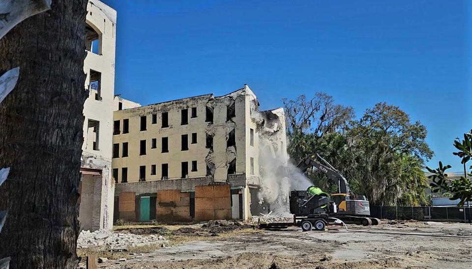 A water cannon, used to control dust, sprays the east wing of the Hotel Putnam as it crumbles on Monday in downtown DeLand.