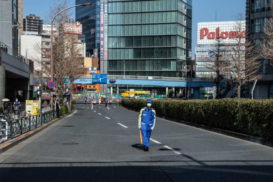 TOKYO, JAPAN - MARCH 01: A security guard wearing a face mask guards a road near the route of the Tokyo Marathon on March 1, 2020 in Tokyo, Japan. The 2020 Tokyo Marathon has been restricted to elite runners only as measures get underway in Japan to combat the Covid-19 virus. A growing number of events and sporting fixtures have been cancelled or postponed while some businesses are closing or asking their employees to work from home. Prime Minister Shinzo Abe has also asked schools to close for around a month from tomorrow as coronavirus cases increase and concerns mount over the effect the outbreak will have on the Tokyo Olympics. (Photo by Carl Court/Getty Images)