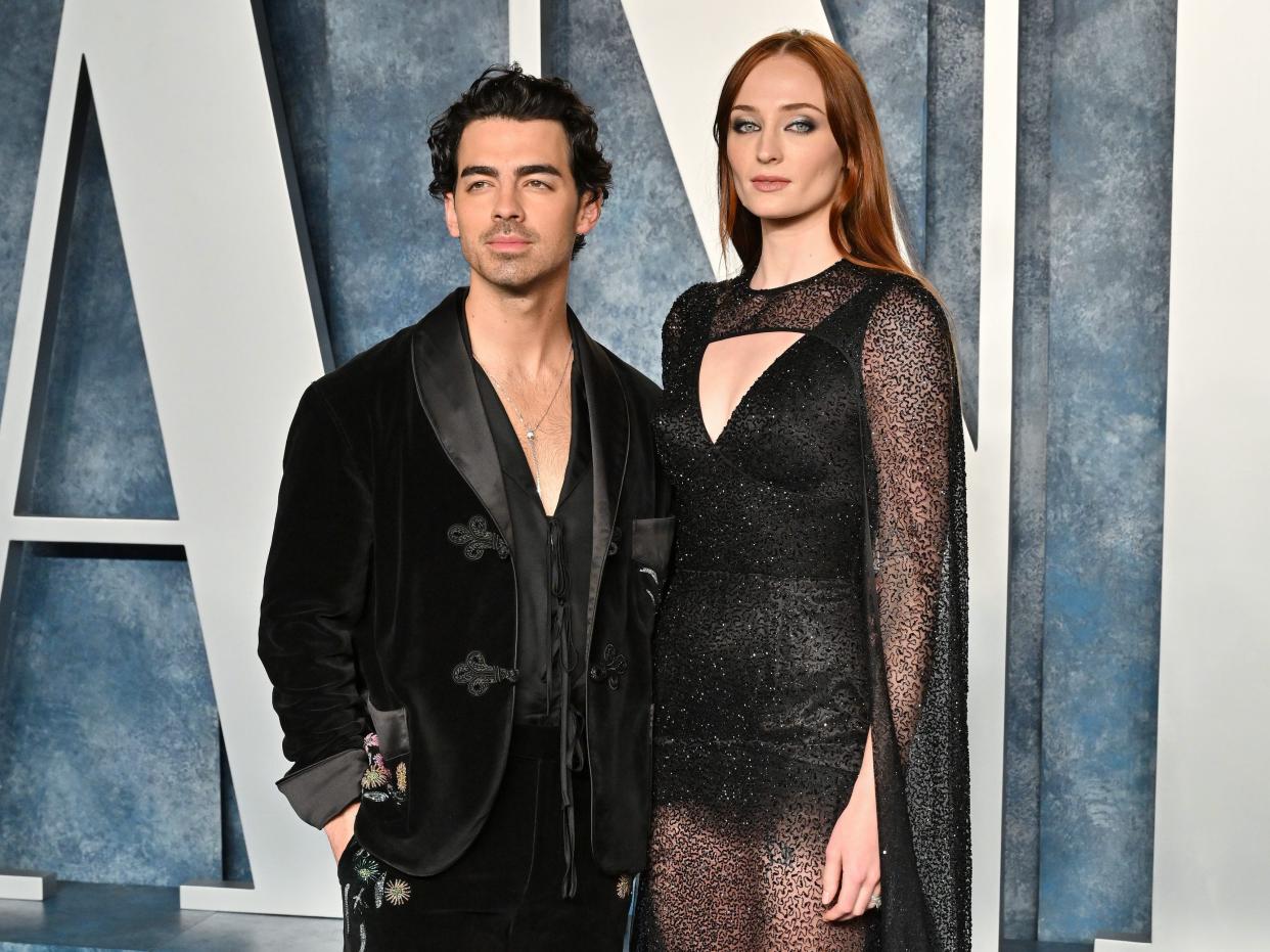 Joe Jonas and Sophie Turner pose together on a blue carpet for a Vanity Fair event