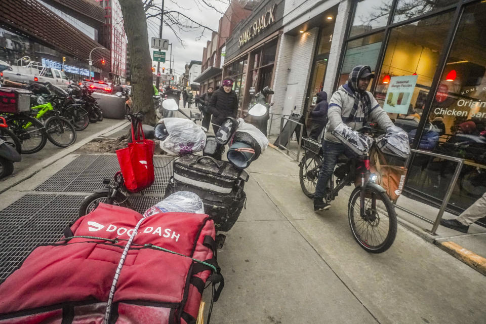 A food delivery worker rides off after a pickup from a fast-food restaurant on Brooklyn's Flatbush Avenue, Monday, Jan. 29, 2024, in New York. A wage law in New York City meant to protect food delivery workers is getting backlash from app companies like Uber, GrubHub and DoorDash. (AP Photo/Bebeto Matthews)