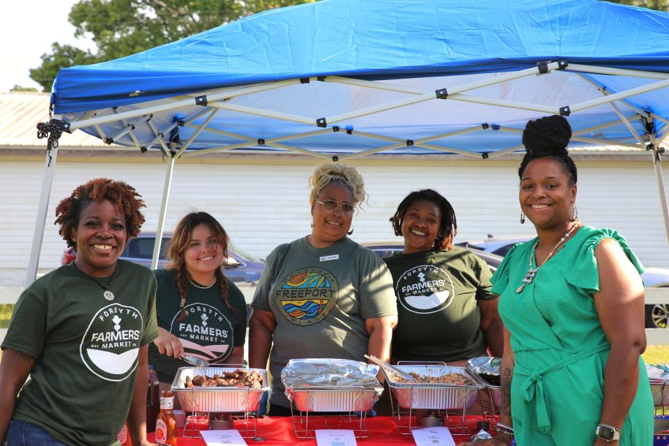 Executive Assistant Dana Hilton, Communications and Events Manager Bella Marchena, Director of Philanthropy Gina Capers-Willis, Director of Community Building Aja Embry, and Executive Director Dr. Deidre Grim (left to right) posing for a photo at the Forsyth Farmers' Market 15th anniversery Farm-R-Que on Sunday, April 28.