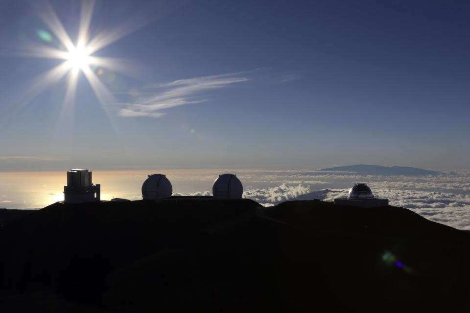 FILE - In this Sunday, July 14, 2019, file photo, the sun sets behind telescopes at the summit of Mauna Kea. Opponents of the Thirty Meter Telescope project on Hawaii island have left their camp because of concerns over the spread of the coronavirus. The Honolulu Star-Advertiser reports the move came after more than eight months of nonviolent protests at the base of the Mauna Kea Access Road. (AP Photo/Caleb Jones, File)