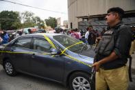 A policeman guards a car used by alleged gunmen outside the Pakistan Stock Exchange building in Karachi on June 29, 2020. - Gunmen attacked the Pakistan Stock Exchange in Karachi on June 29, with four of the assailants killed, police said. (Photo by Asif HASSAN / AFP) (Photo by ASIF HASSAN/AFP via Getty Images)