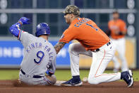 Houston Astros shortstop Carlos Correa (1) loses the ball between his legs before he attempts the tag on Texas Rangers' Isiah Kiner-Falefa (9) as he doubles during the seventh inning of a baseball game Friday, May 14, 2021, in Houston. (AP Photo/Michael Wyke)