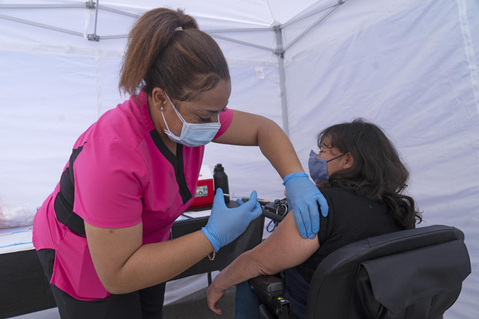 Veronica Lopez, who has Spina bifida and is a resident of the 90255 ZIP code, is vaccinated by medical assistant Keyaira Excoe at the St. John's Well Child and Family Center's COVID-19 vaccination site at the East Los Angeles Civic Center in Los Angeles, Thursday, March 4, 2021. California will begin setting aside 40% of all vaccine doses for the state's most vulnerable neighborhoods in an effort to inoculate people most at risk from the coronavirus more quickly. (AP Photo/Damian Dovarganes)