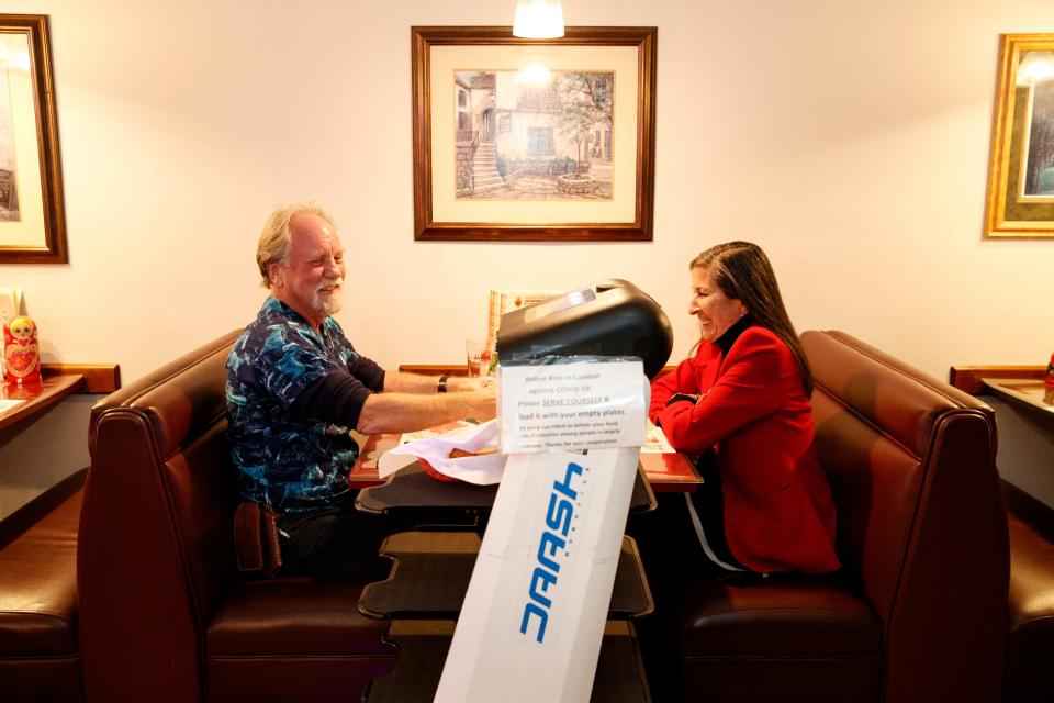 Robot Rosi ferries salad and bread to Kevin, left, and Maria Fenton inside Haus of Pizza in Palm Desert, Calif., on Jan. 10, 2022. After having difficulty finding workers despite raising wages, Haus of Pizza took the innovative step of leasing a serving robot. 