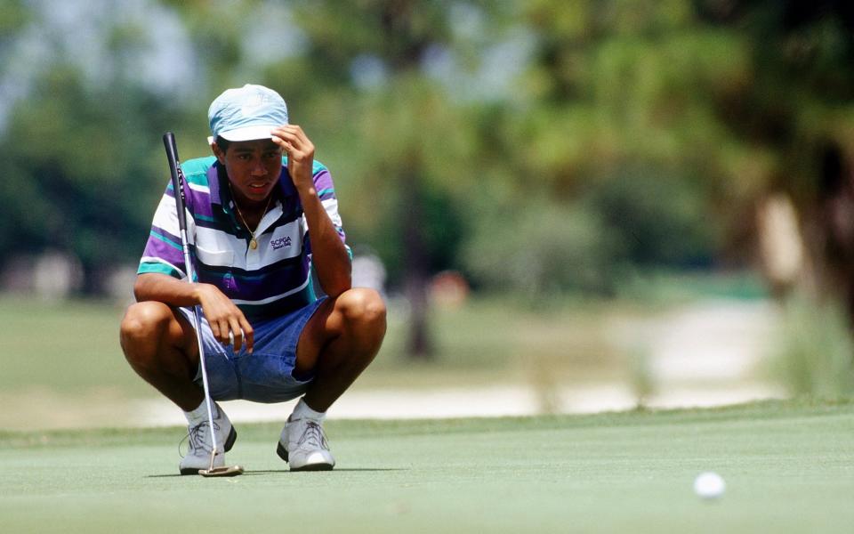 Woods, aged 14, lines up a putt at the PGA Junior Championships in 1990 - GETTY IMAGES