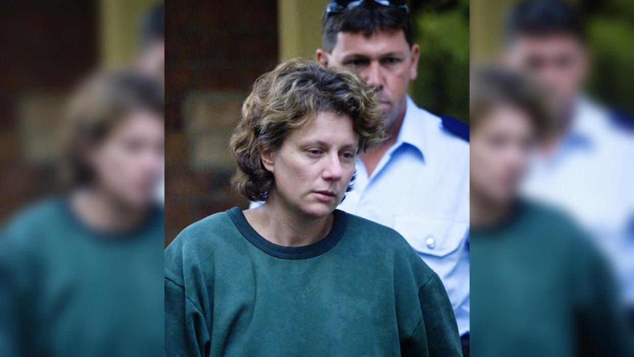  A woman in a green jumper with short brown hair being escorted  out of a courtroom 