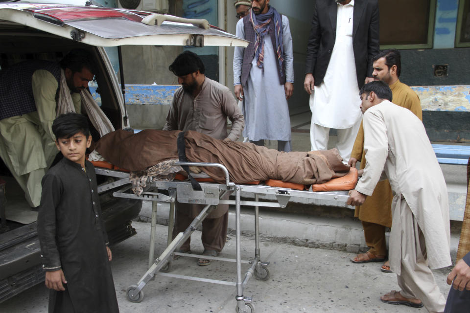 Afghan carry body of a woman who was killed in a stampede the city of Jalalabad east of Kabul, Afghanistan, Wednesday, Oct. 21, 2020. At least 11 women were trampled to death when a stampede broke out Wednesday among thousands of Afghans waiting in a soccer stadium to get visas to Pakistan, officials said. (AP Photo/Wali Sabawoon)