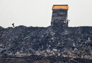 In this Oct. 23, 2019, photo, a laborer keeps watch as coal is unloaded from a truck in the village of Rajapur in Jharia, a remote corner of eastern Jharkhand state, India. The fires started in coal pits in eastern India in 1916. More than a century later, they are still spewing flames and clouds of poisonous fumes into the air, forcing residents to brave sizzling temperatures, deadly sinkholes and toxic gases. (AP Photo/Aijaz Rahi)